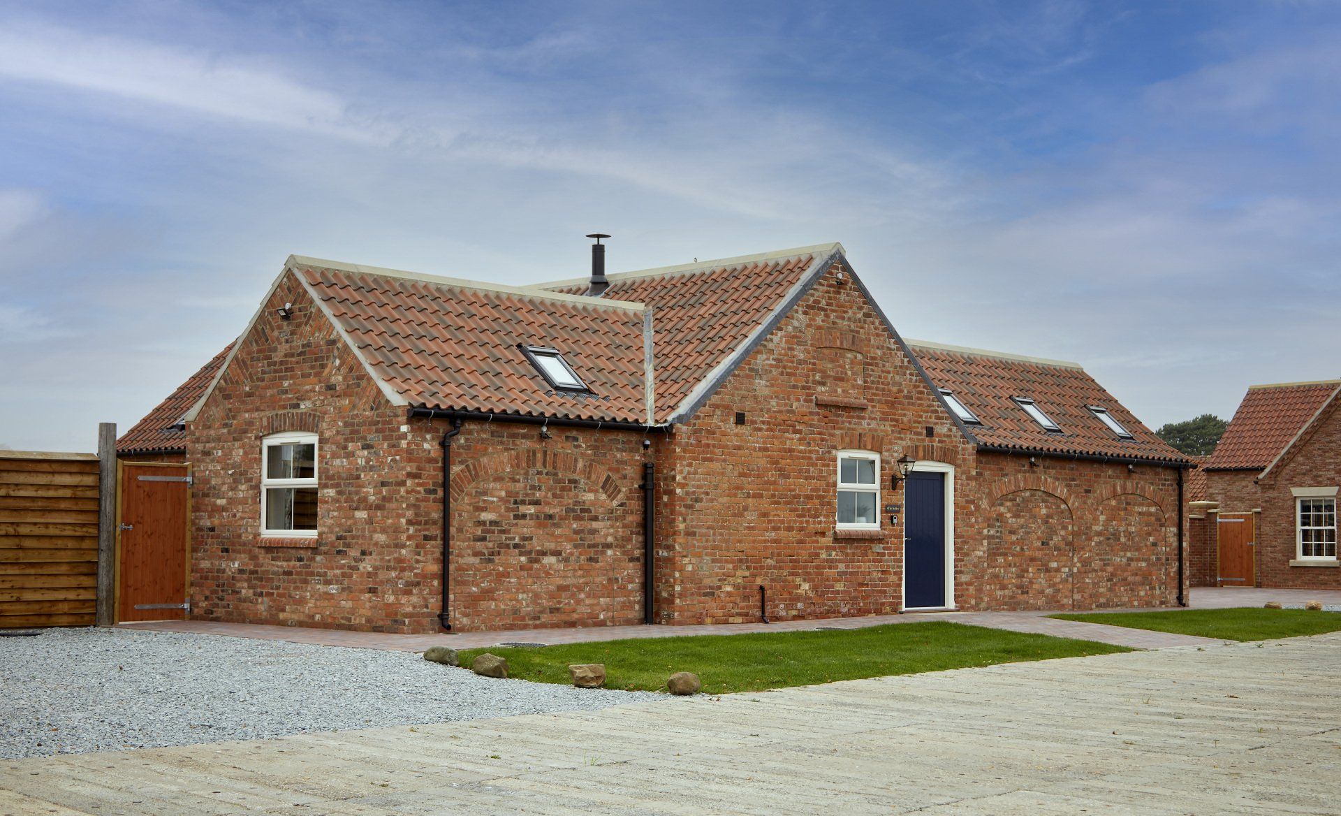 A brick house with a blue door and a blue sky in the background.