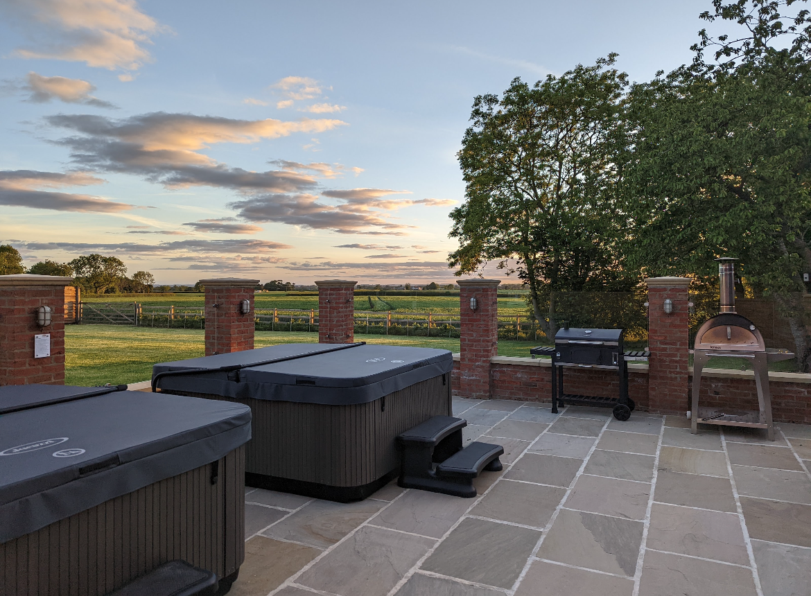 A patio with two hot tubs and a grill.