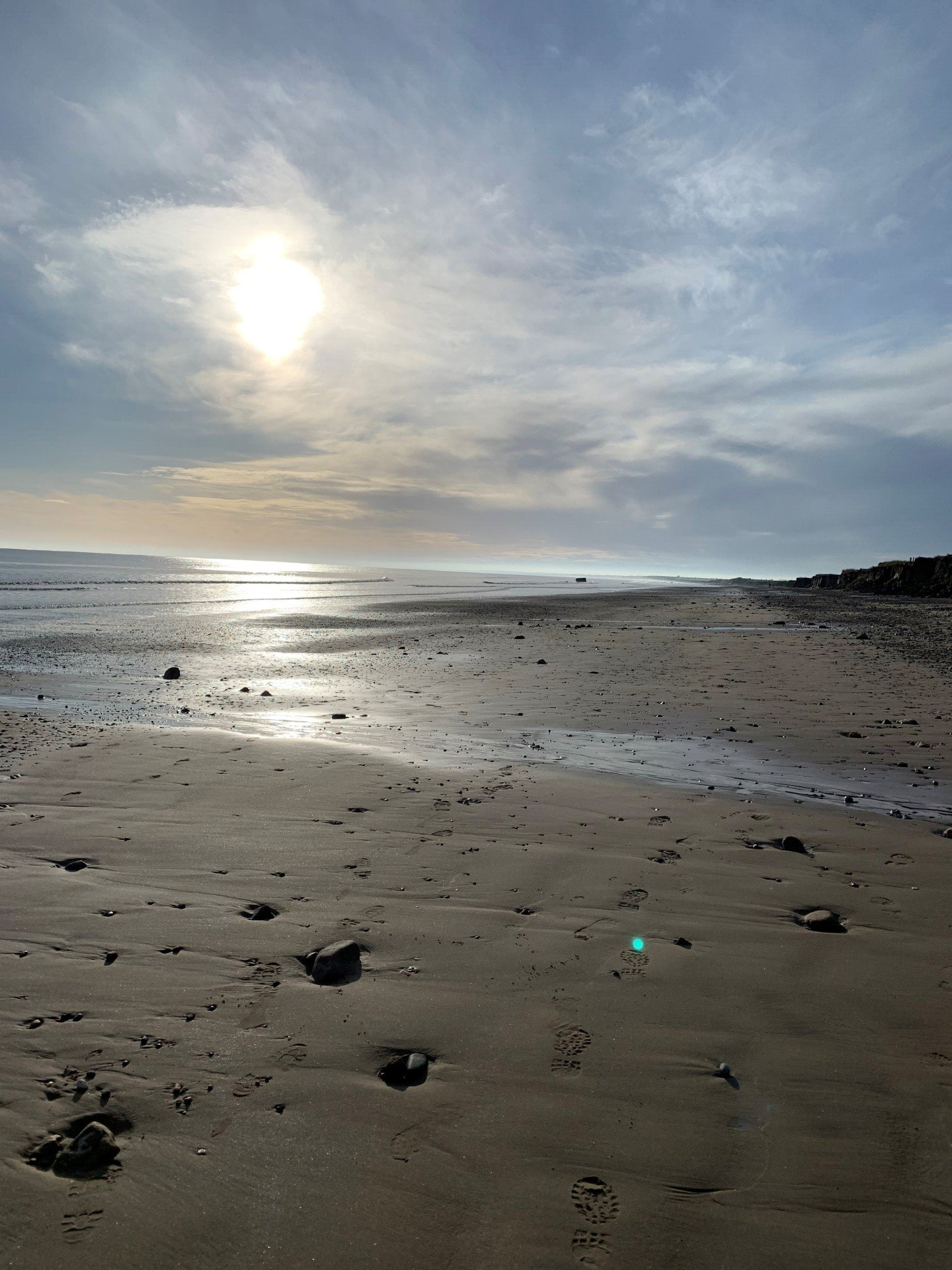 A beach with the sun shining through the clouds