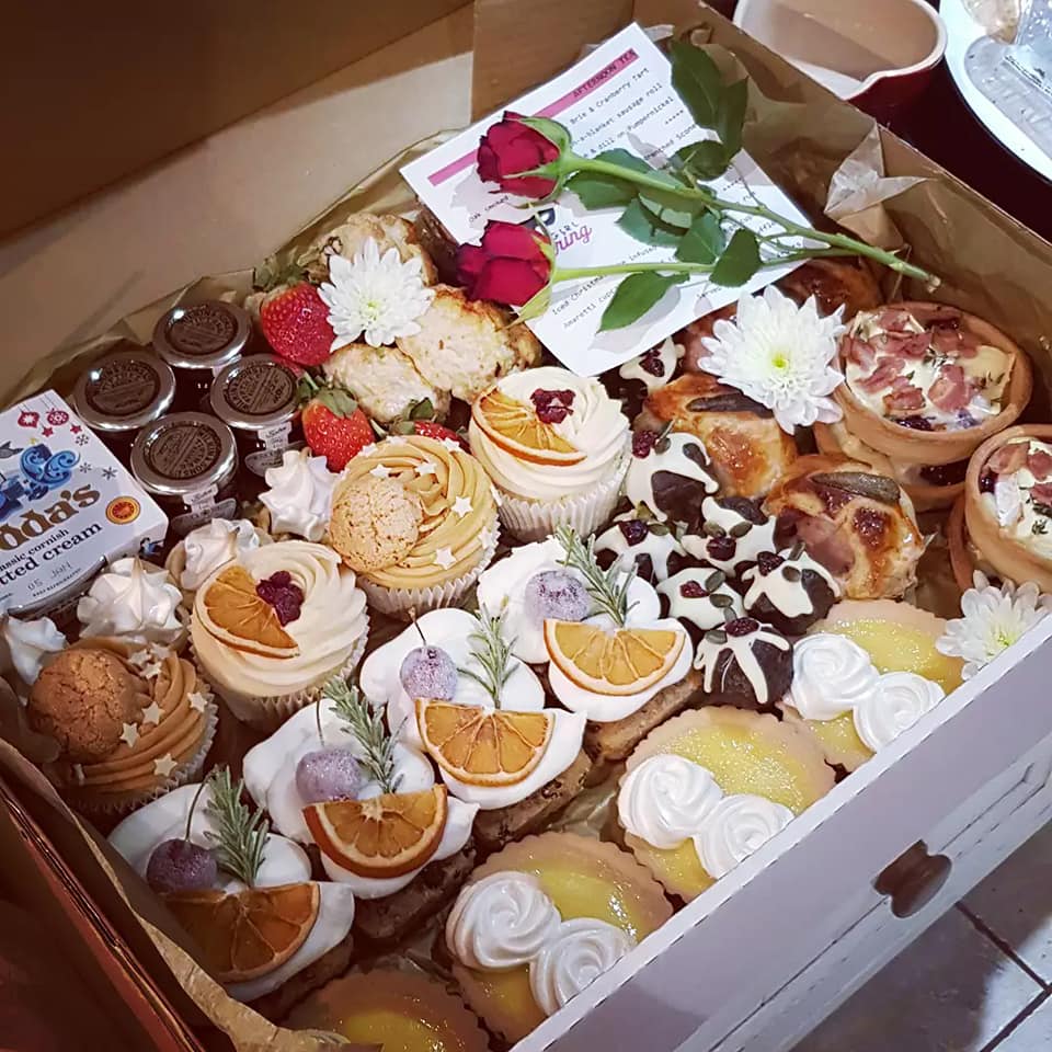 A box filled with cupcakes , pastries , and flowers.