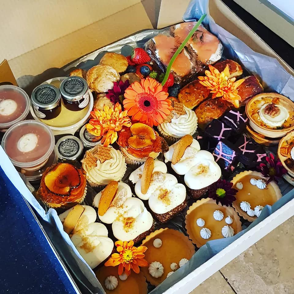 A box filled with a variety of desserts and flowers