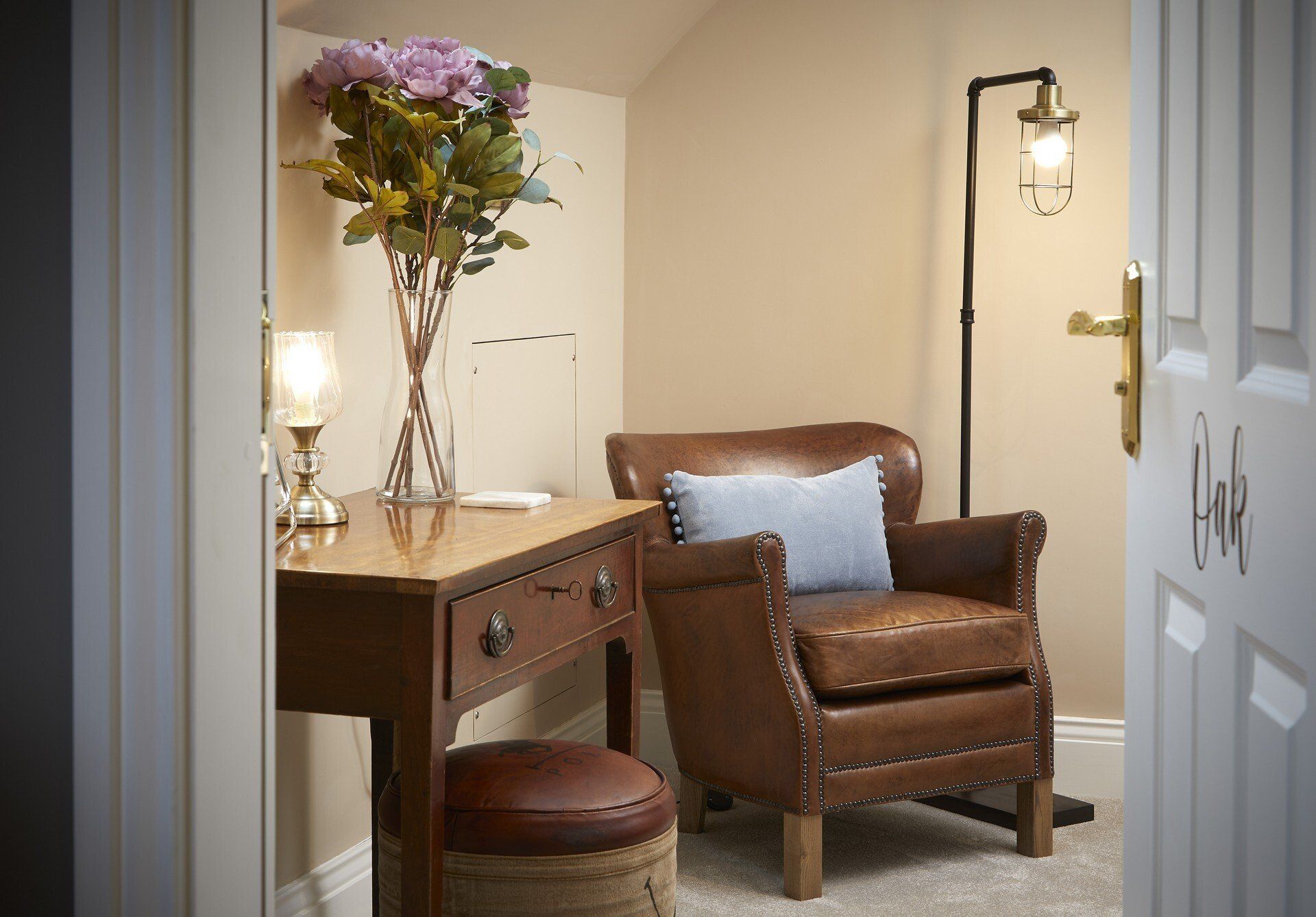 A chair is sitting next to a desk with a vase of flowers on it.