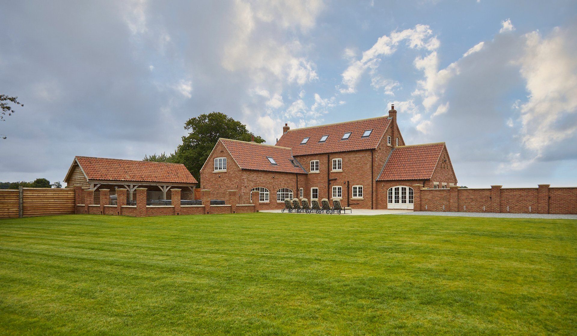 A large brick house with a large lawn in front of it.