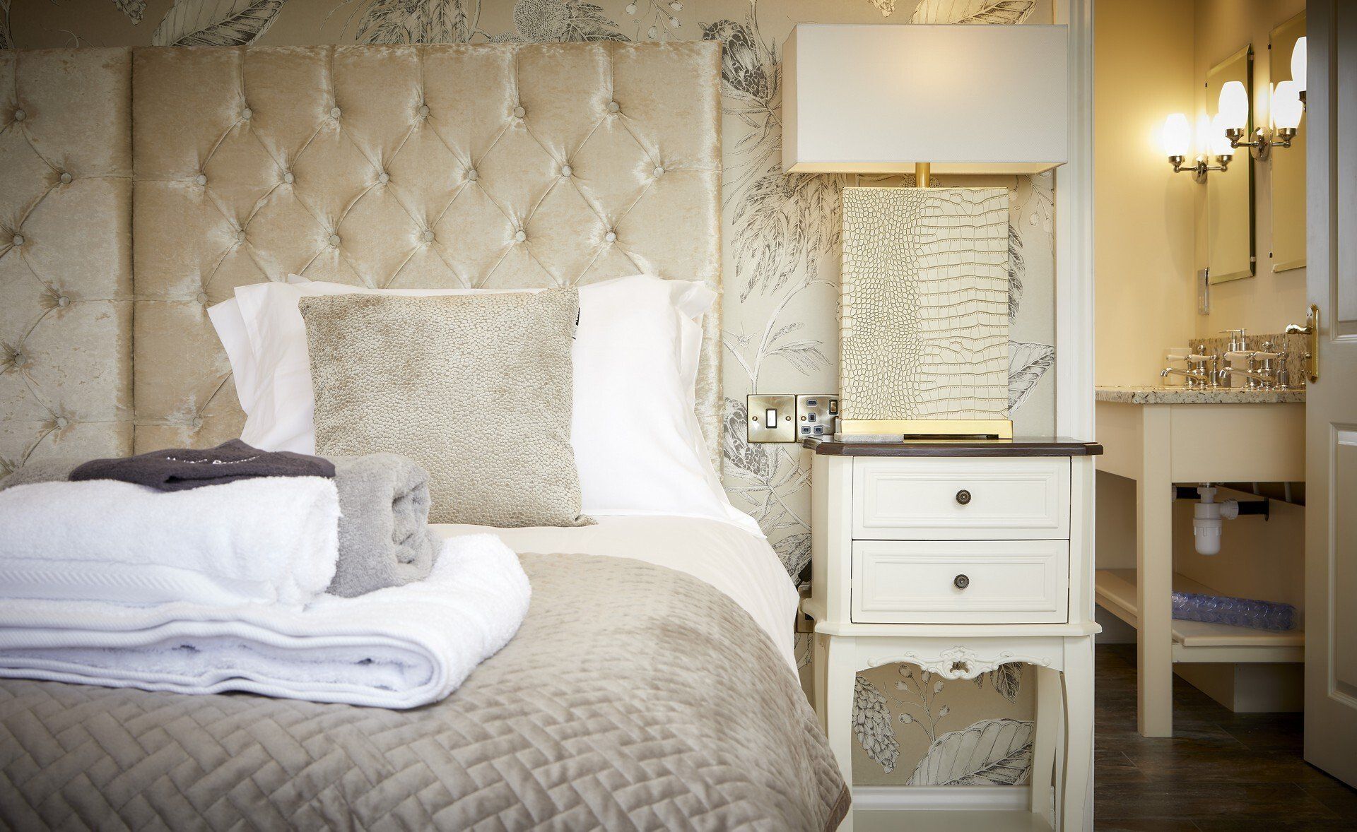 A bedroom with a bed , nightstand , and lamp.