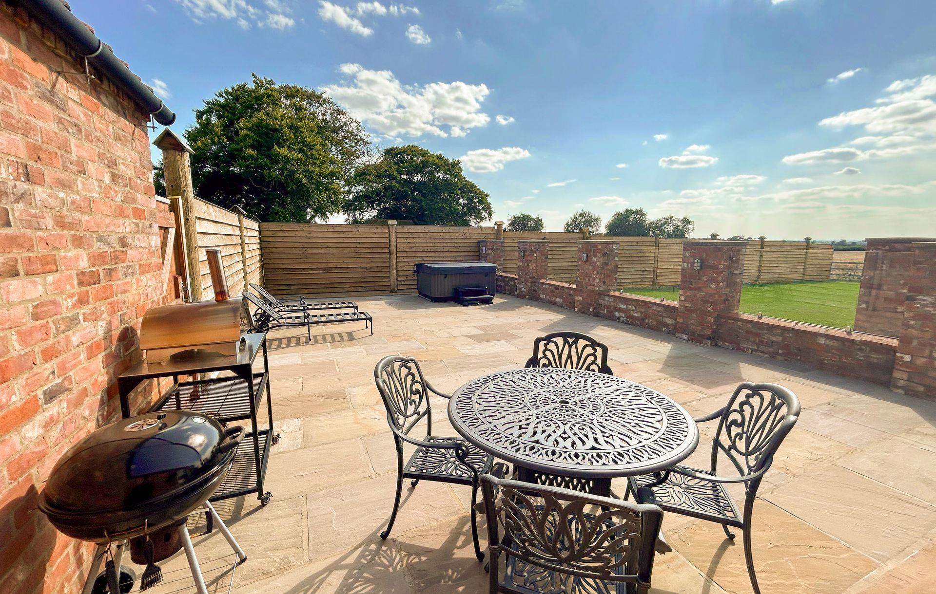 A patio with a table and chairs and a grill.