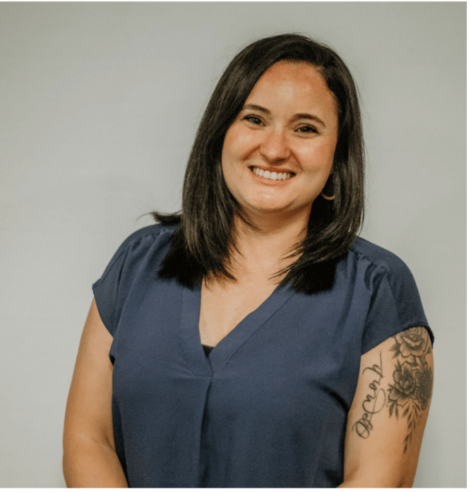 A woman with a tattoo on her arm is smiling for the camera.