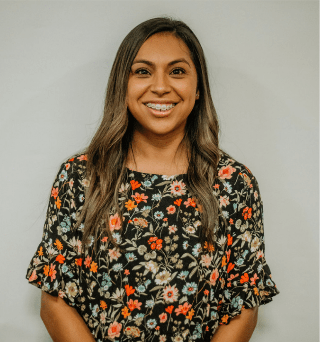 A woman wearing a floral shirt is smiling for the camera.