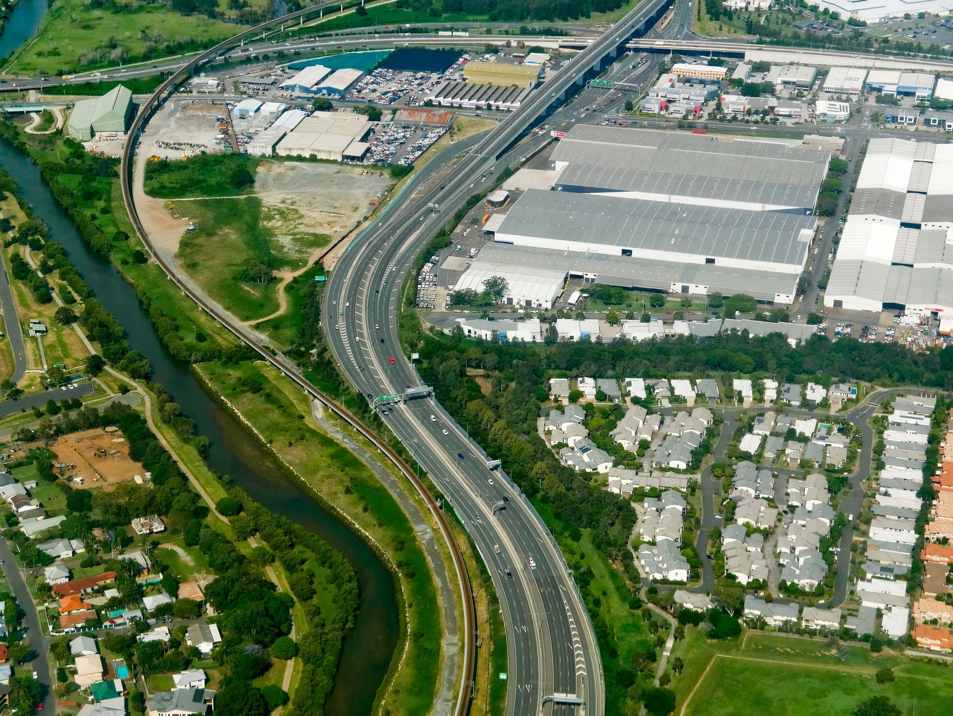 Aerial View: Highway Curves Alongside a River and Residential Area — J'adore Flowers & Gifts Cairns in Bungalow, QLD