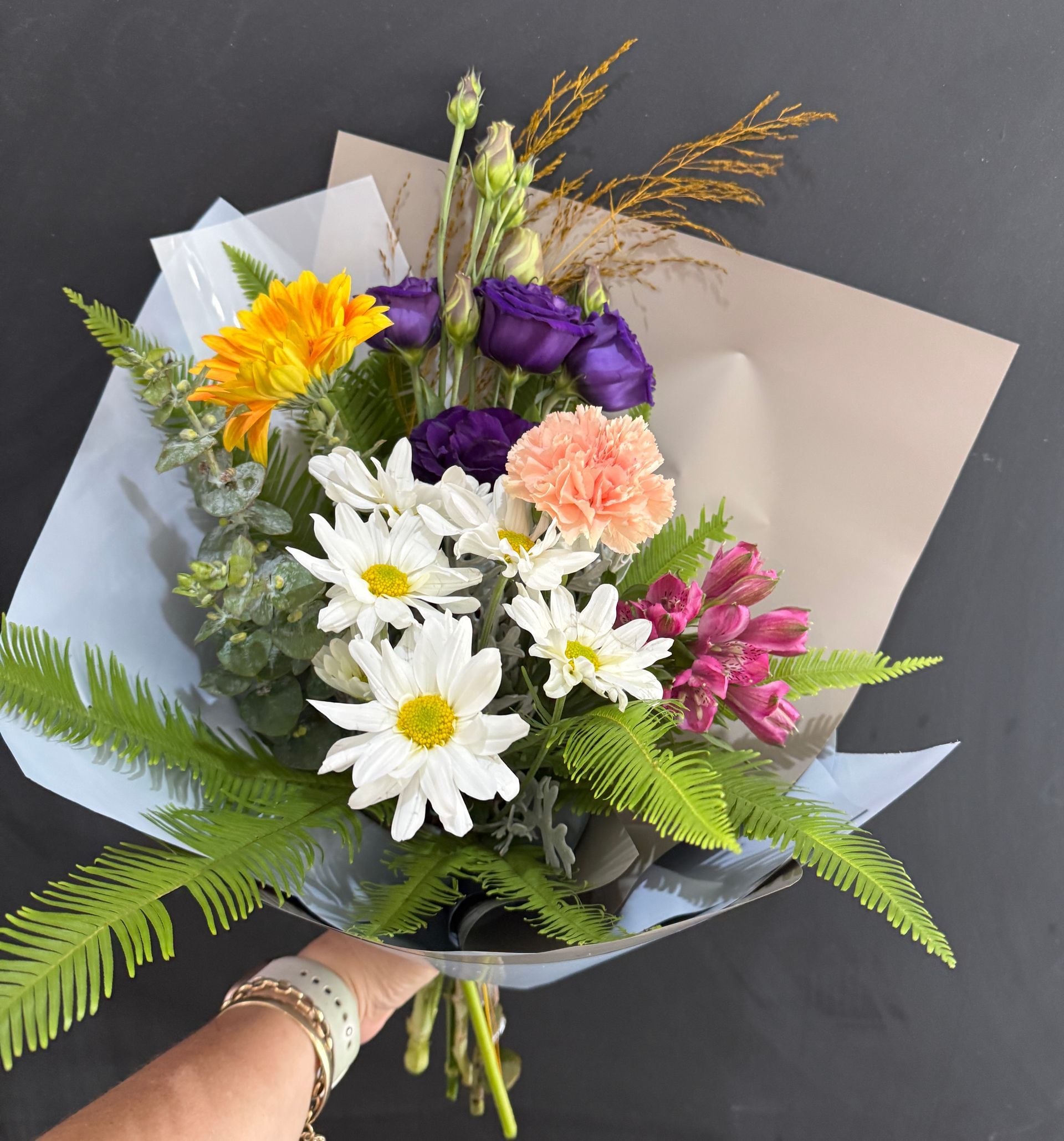Bouquet of yellow, white, purple, and pink flowers in tan and blue paper, held by a person — J'adore Flowers & Gifts Cairns in Earlville, QLD