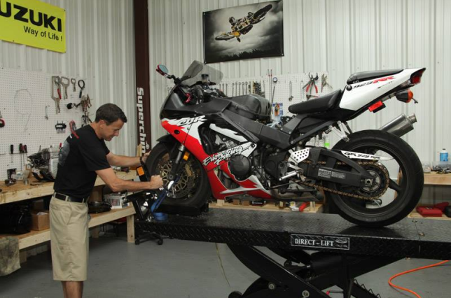 A man is working on a motorcycle in a suzuki garage