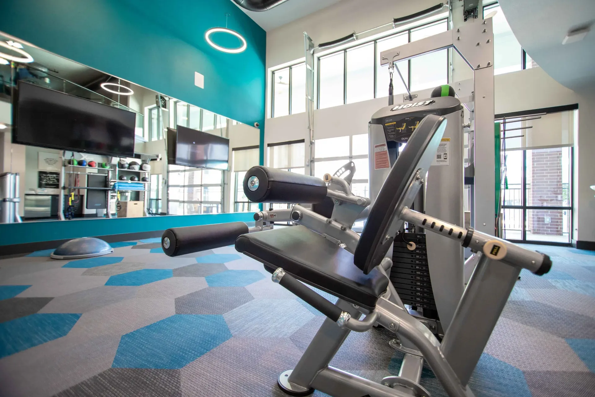Modern gym with a weight machine, mirrors, and teal walls.