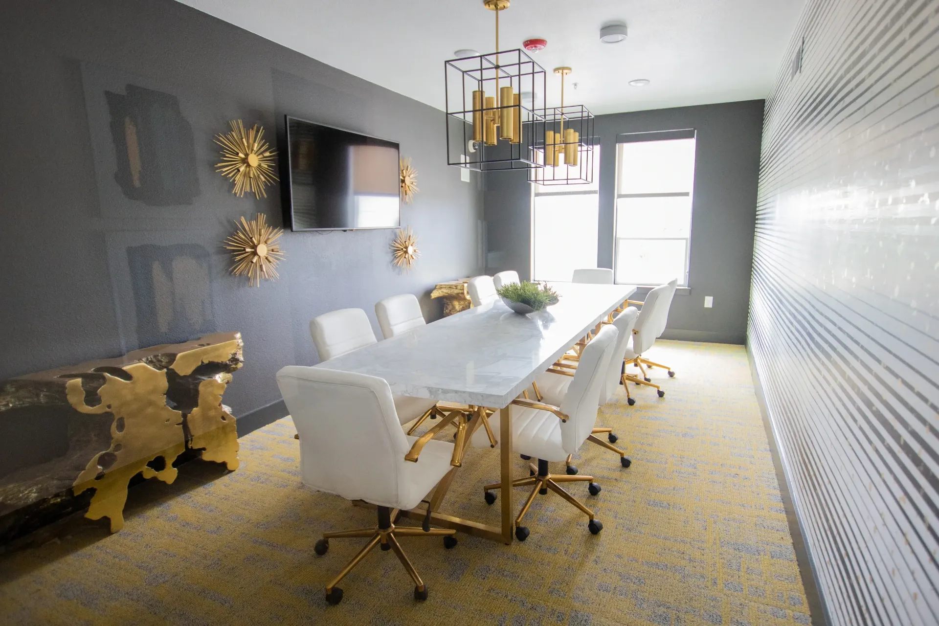 Modern community conference room with a long marble table and white chairs.