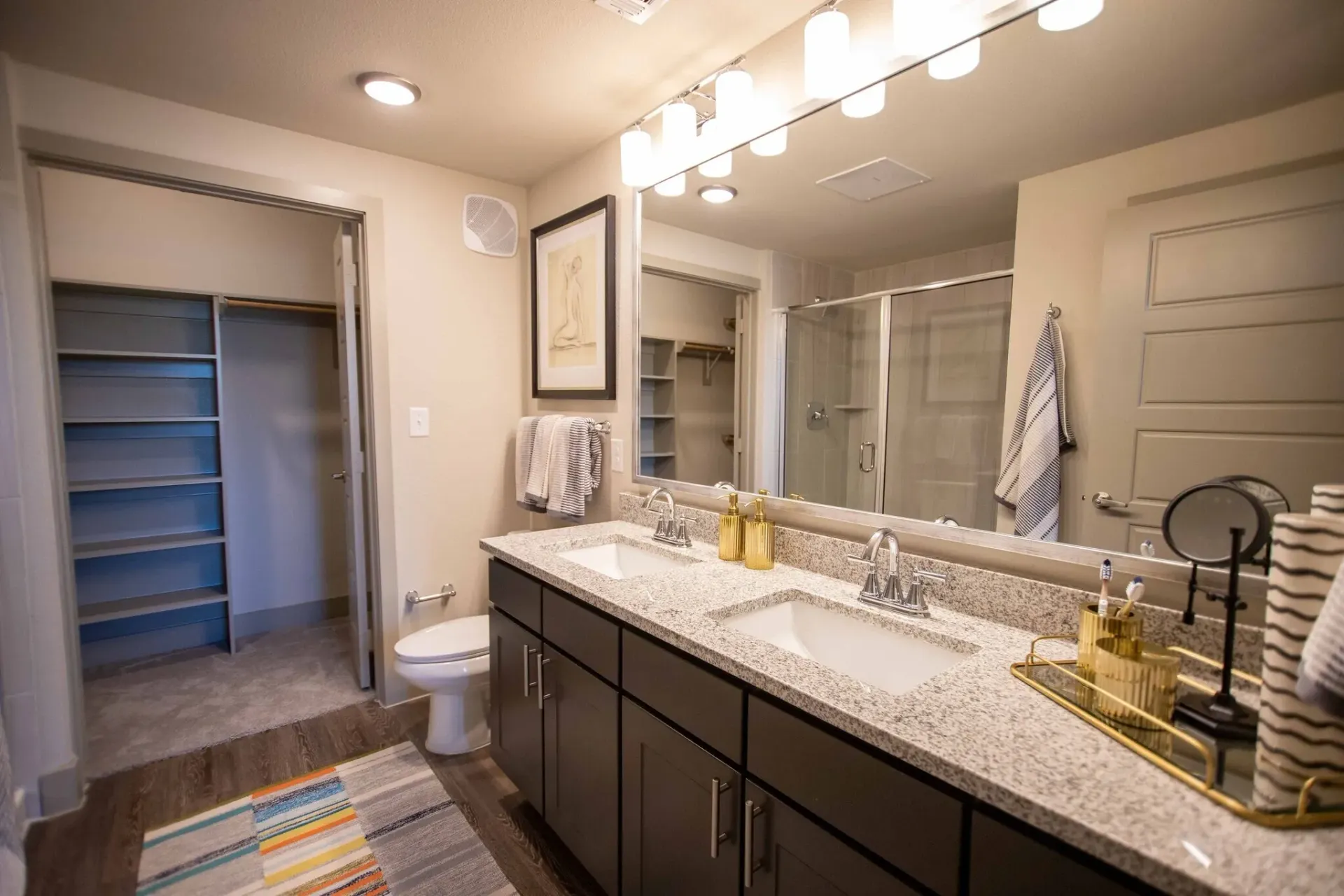 Double-sink bathroom vanity with granite countertop and large mirror in a modern apartment.