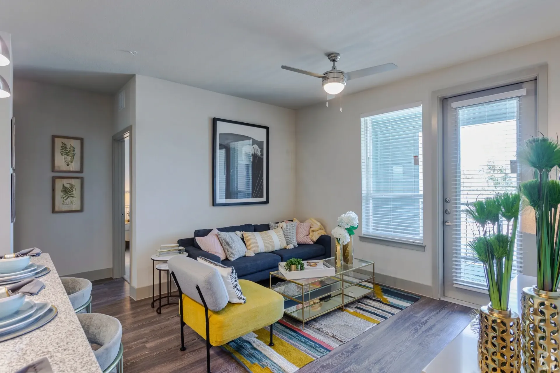 Living room in an apartment with a dark blue sofa, colorful cushions, and large windows.