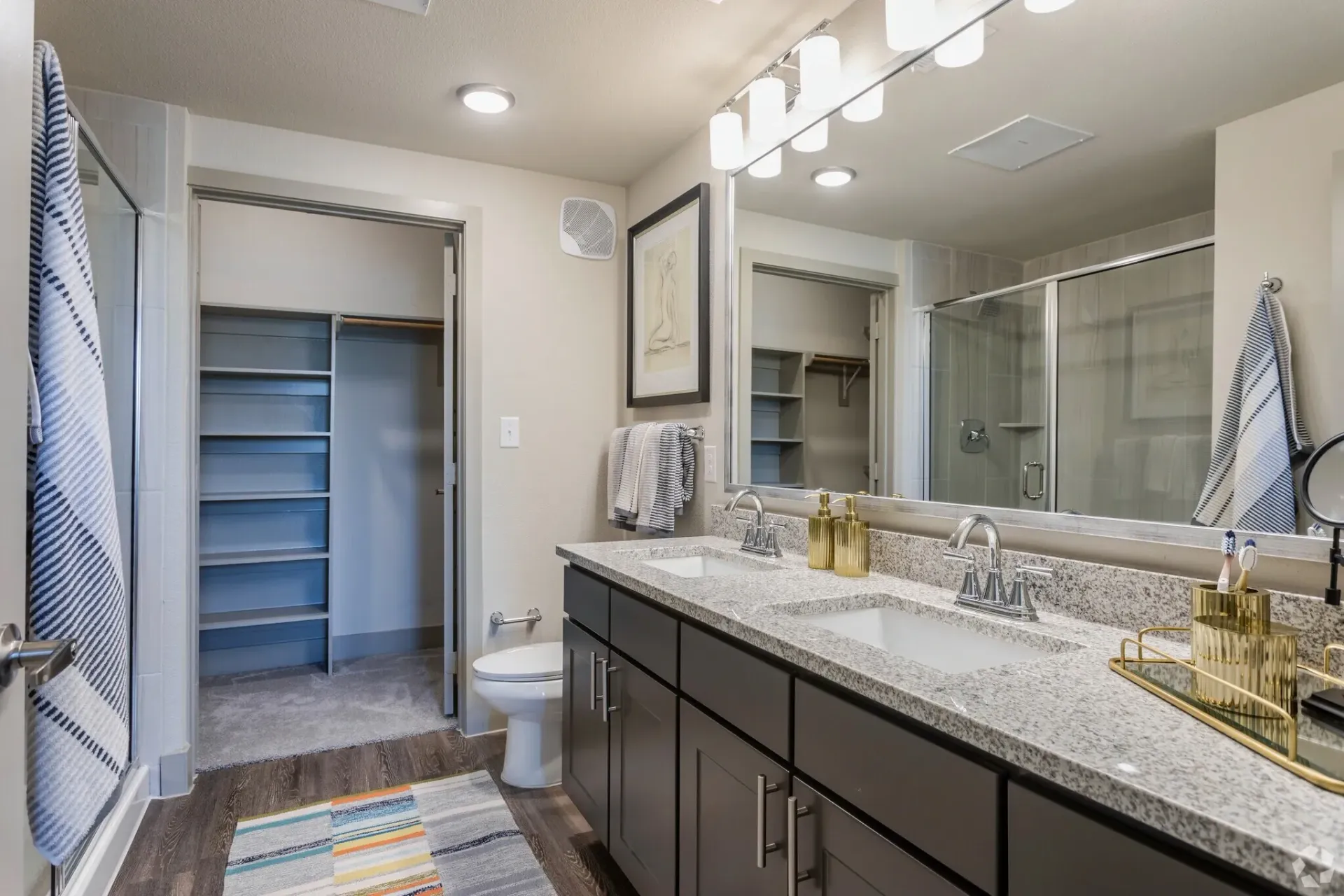 Bathroom with a double vanity, granite countertops, large mirror, and a glass-enclosed shower.
