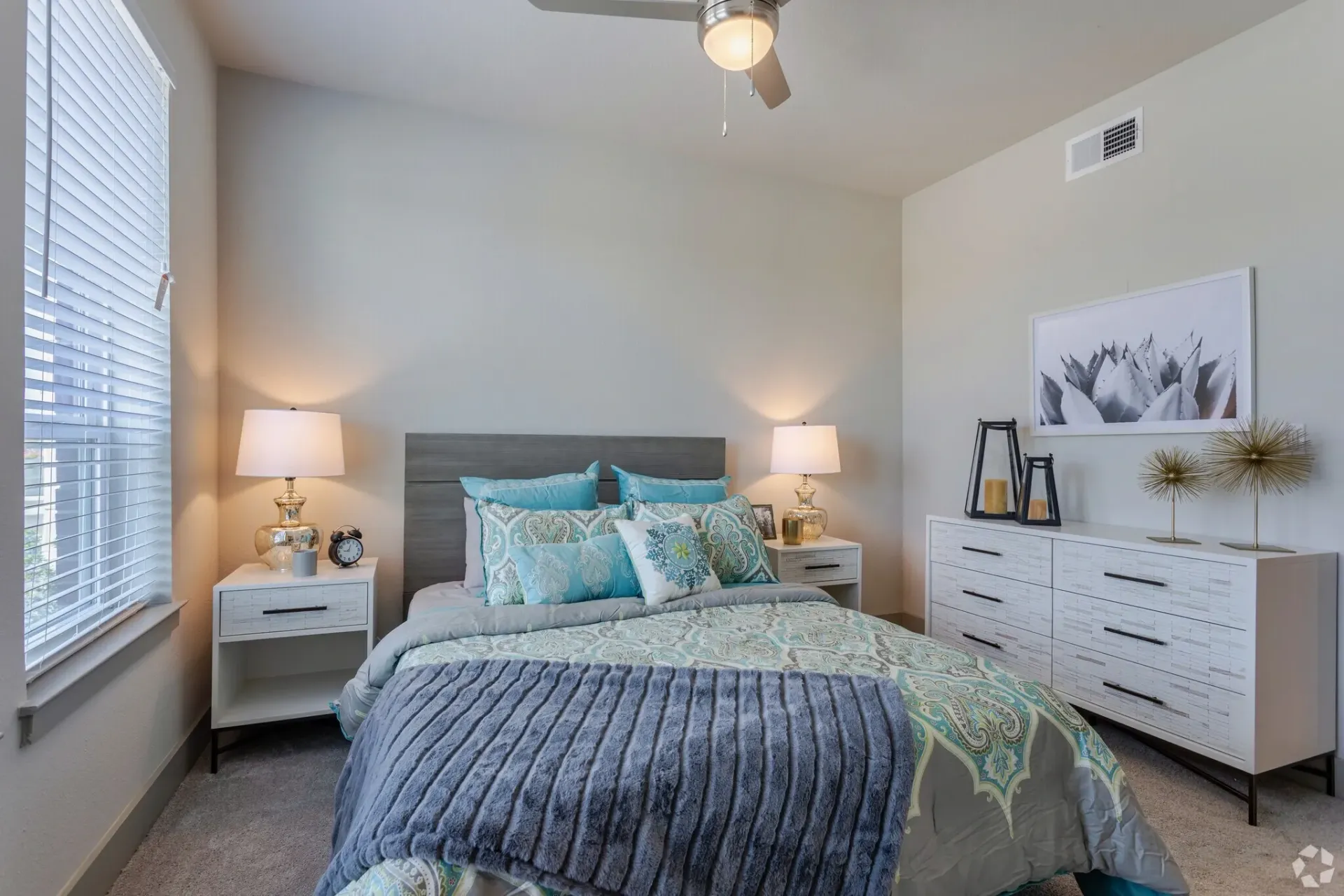 Bedroom in an apartment with a queen bed, two nightstands, and a white dresser.