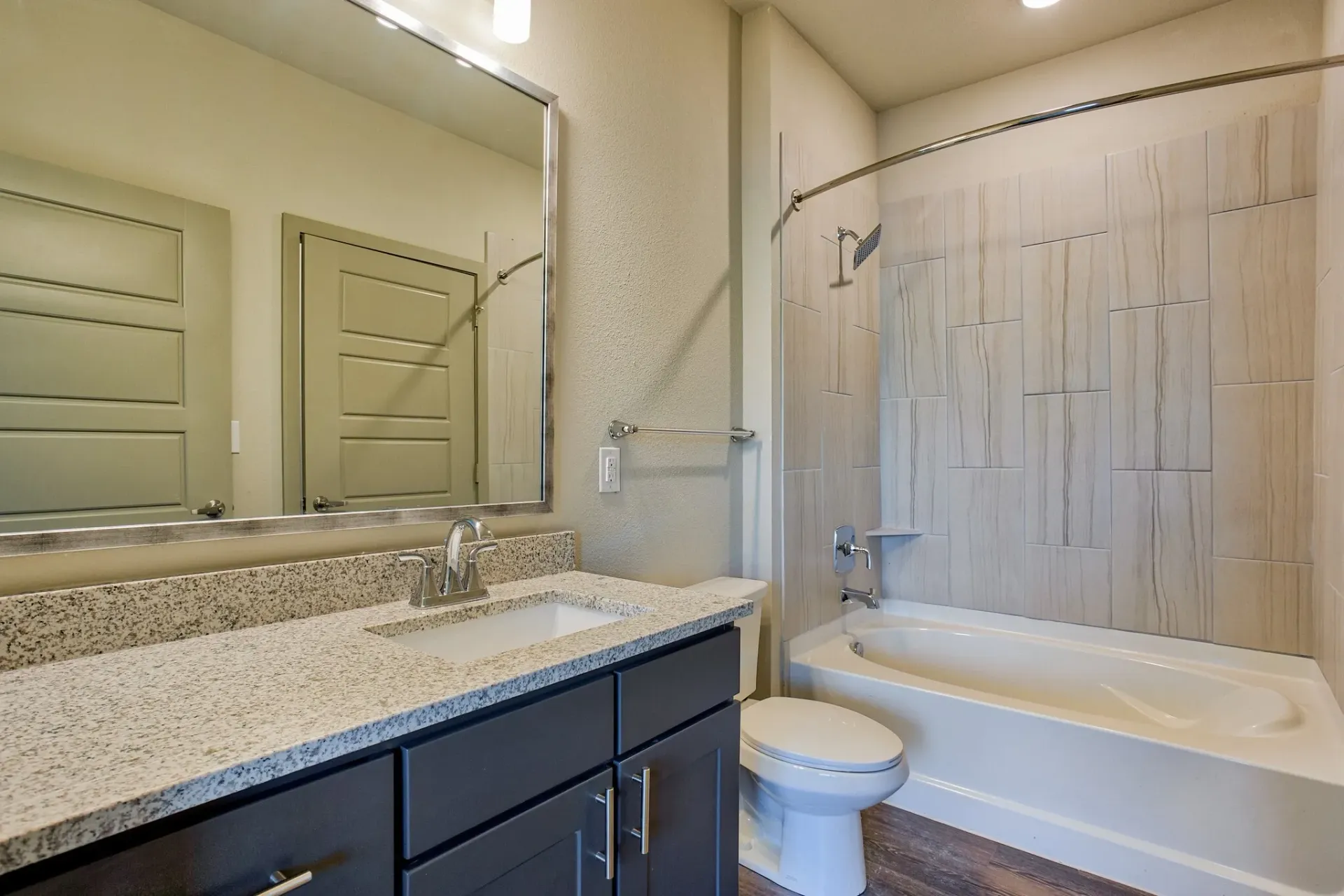 Bathroom featuring a granite vanity, single sink, toilet, and a tiled bathtub/shower combo.
