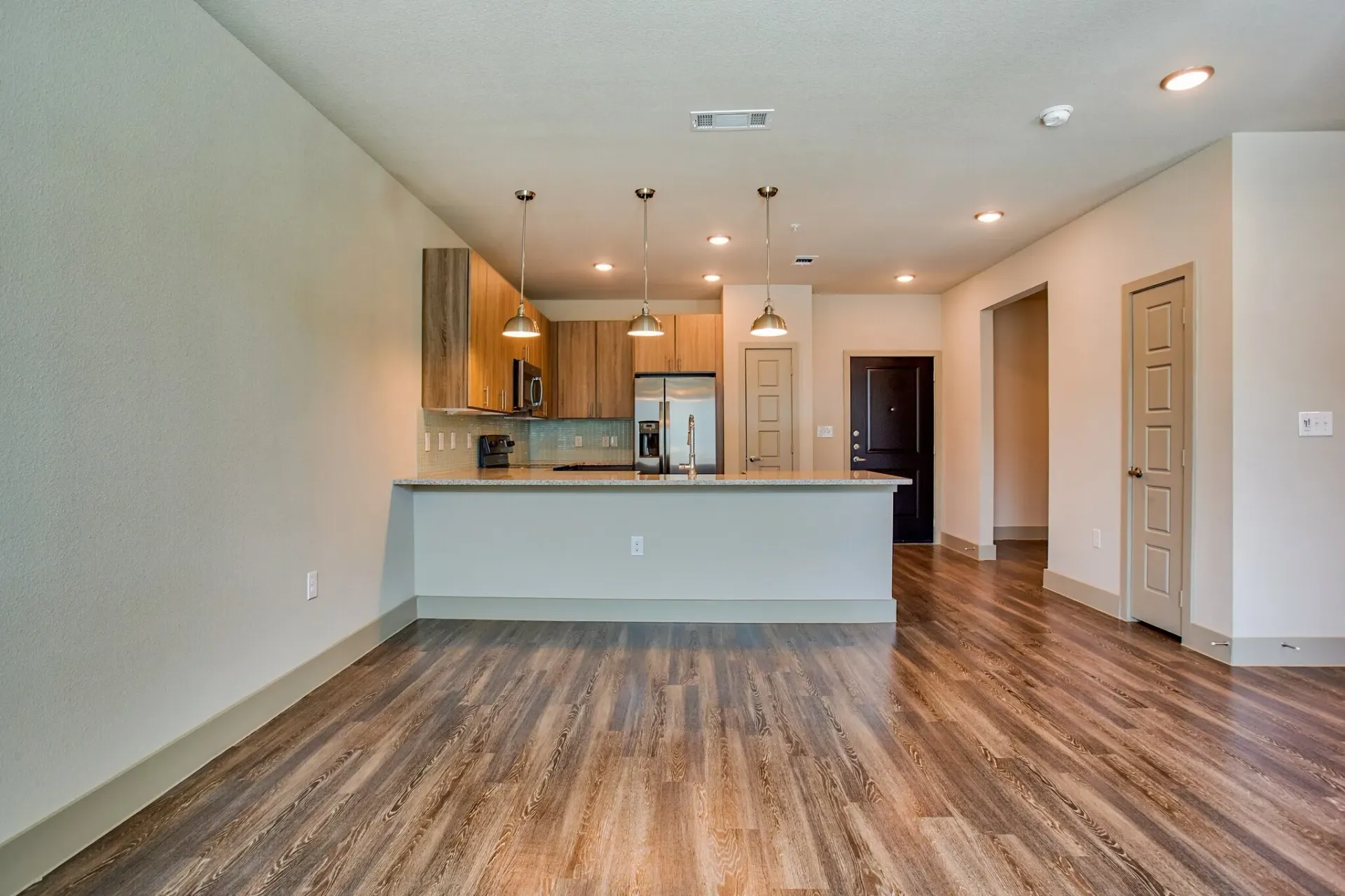 Open-concept kitchen with island, wood cabinets, and stainless steel appliances.