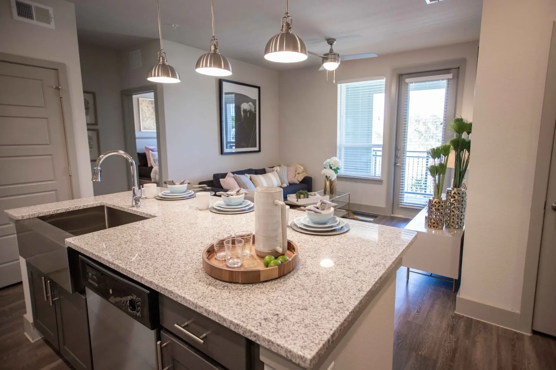 Open-concept kitchen with granite island, dining setup, and living area with balcony door.