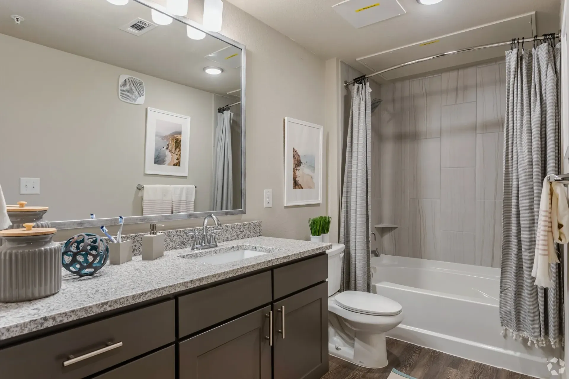 Bathroom with granite countertop, single sink, large mirror, toilet, and tub/shower.