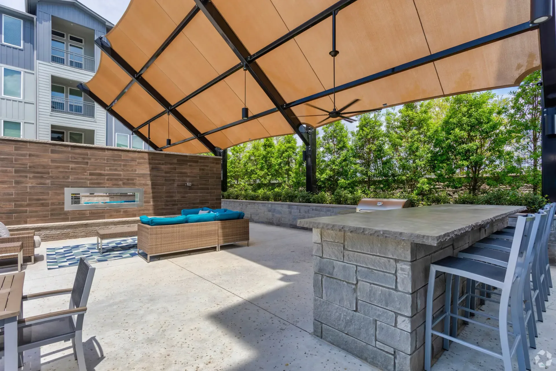 Outdoor communal lounge with a shaded canopy, bar counter, and seating in a residential courtyard.