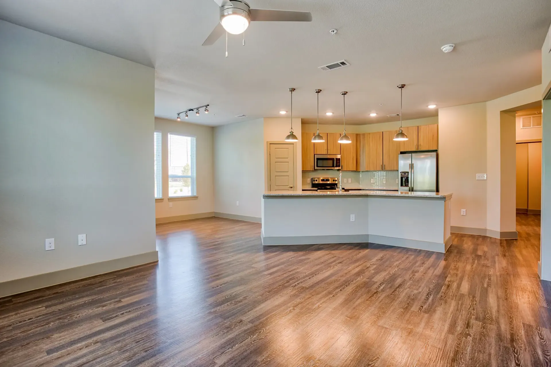 Open-concept living area with island kitchen, pendant lights, and stainless-steel appliances.