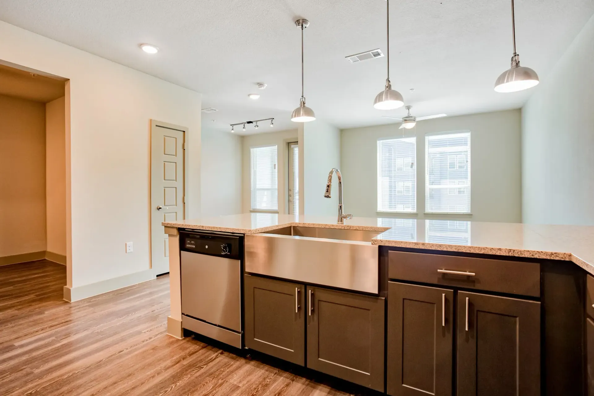 Modern kitchen with an island, stainless steel dishwasher, double sink, and pendant lights.