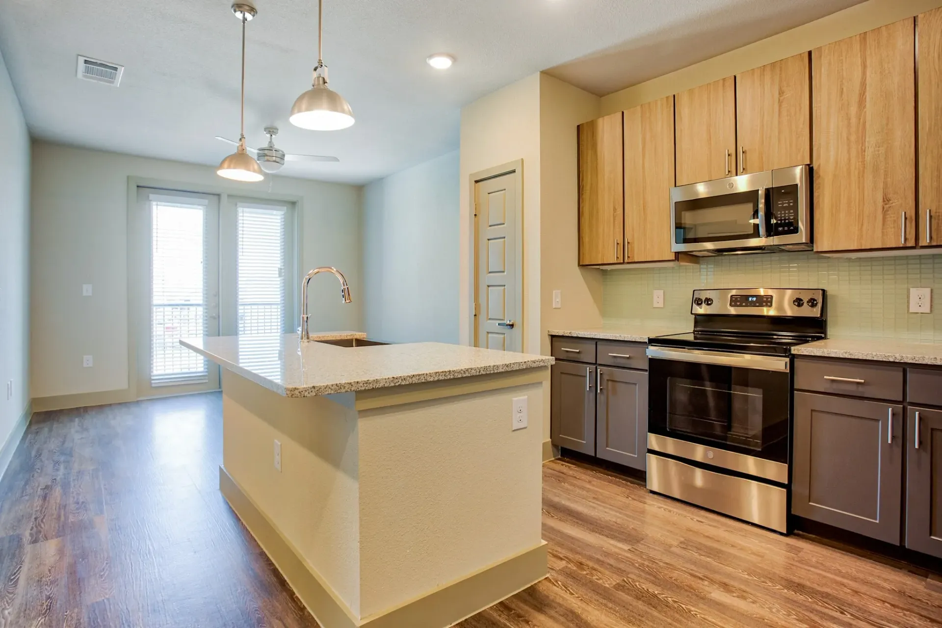 Open-concept apartment kitchen with island, sink, granite countertops, and stainless-steel appliances.