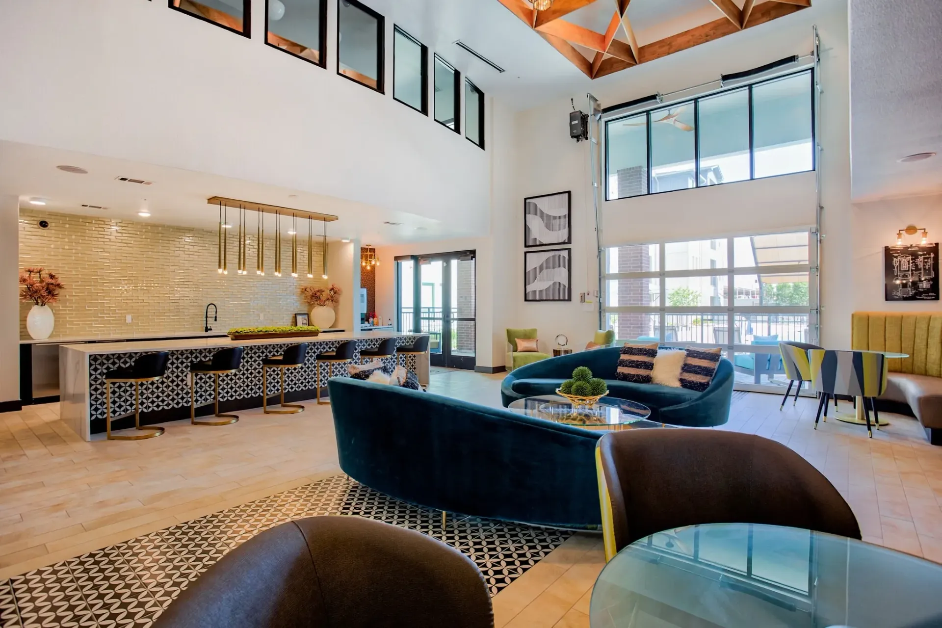 Open, well-lit community lounge with seating, a bar area, and large windows.