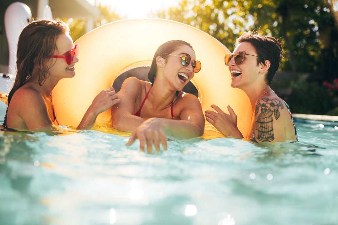 Three people laughing in a swimming pool at Three77 Park in Fort Worth, TX.