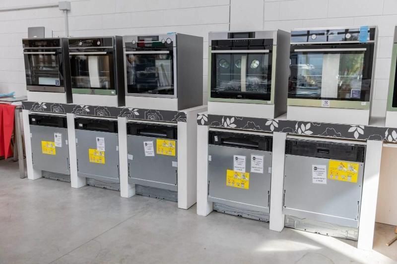 Una reception professionale con scrivania in legno scuro, pavimento in piastrelle grigie lucide e pareti color bordeaux sotto un soffitto metallico.