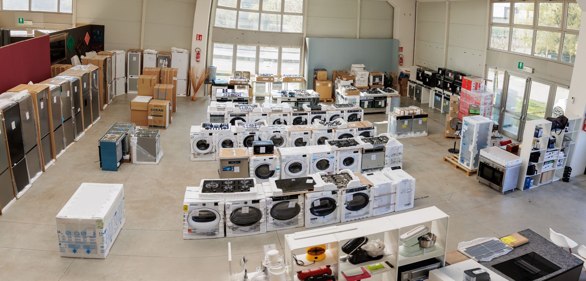 Area reception con pareti color bordeaux, pavimento in piastrelle grigie, bancone scuro a forma di L e un piccolo tavolino bianco.