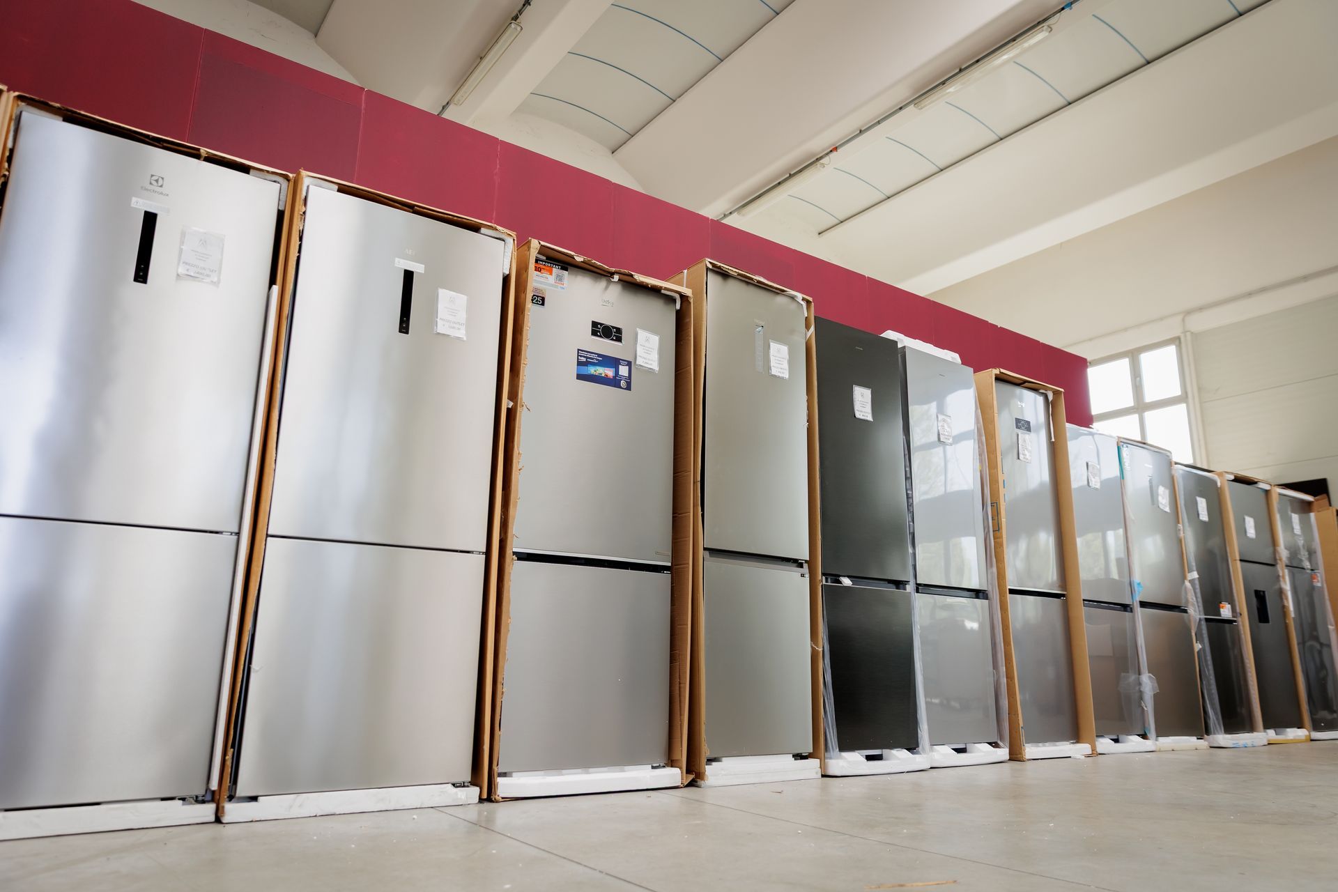 Un frigorifero bianco, una lavastoviglie e una lavatrice a carica frontale disposti su uno sfondo nero.