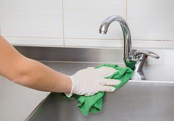 Hand in protective glove with rag cleaning kitchen equipment — Restaurant Equipment & Supplies Retail in Daytona Beach, FL