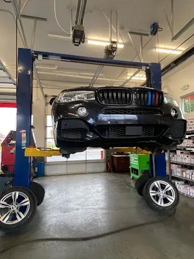 Black BMW SUV on a car lift in a garage, wheels removed.