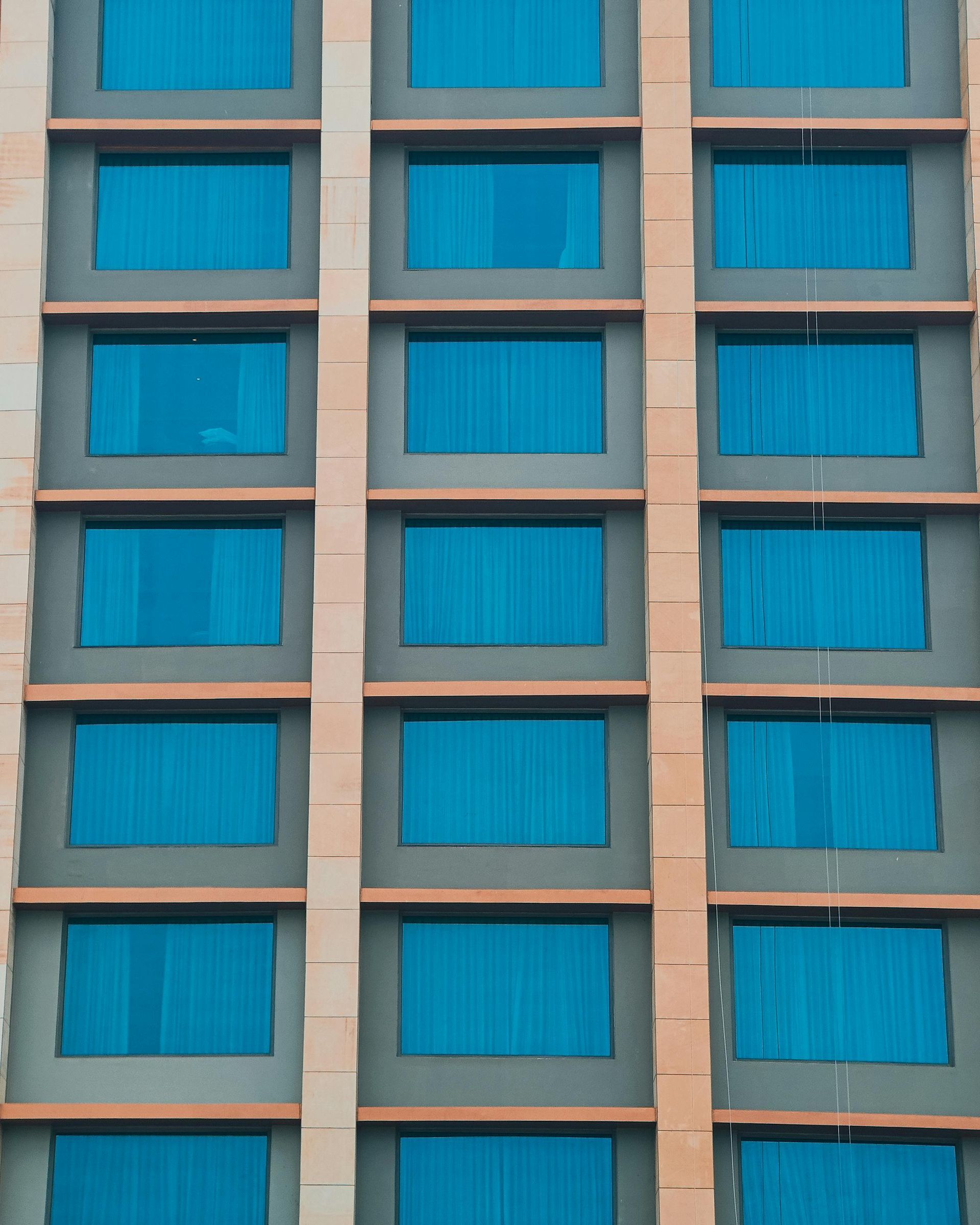 Building facade with rows of blue-tinted windows. Beige and grey exterior.