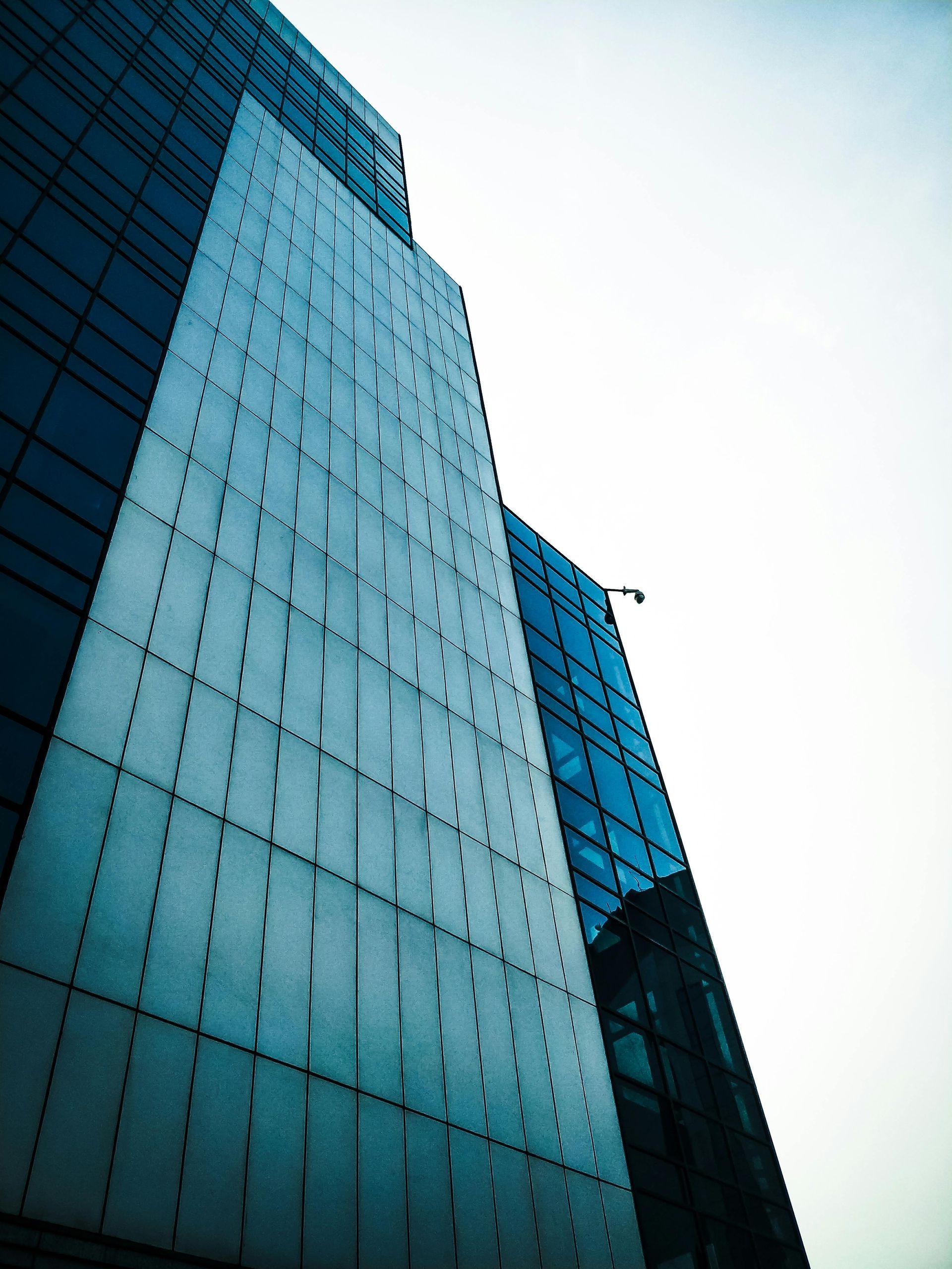 Tall modern building, glass and metal facade against a bright sky.