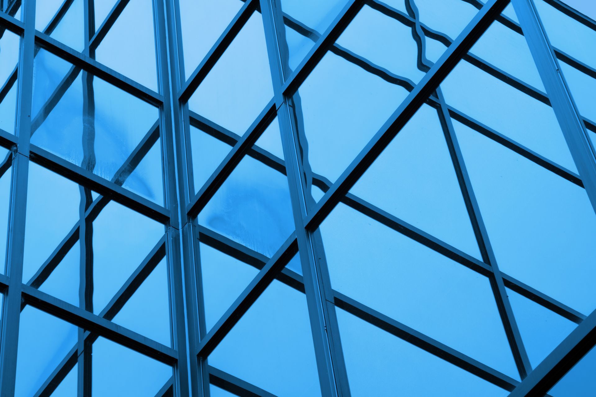 Blue glass skyscraper exterior with geometric metal frame.