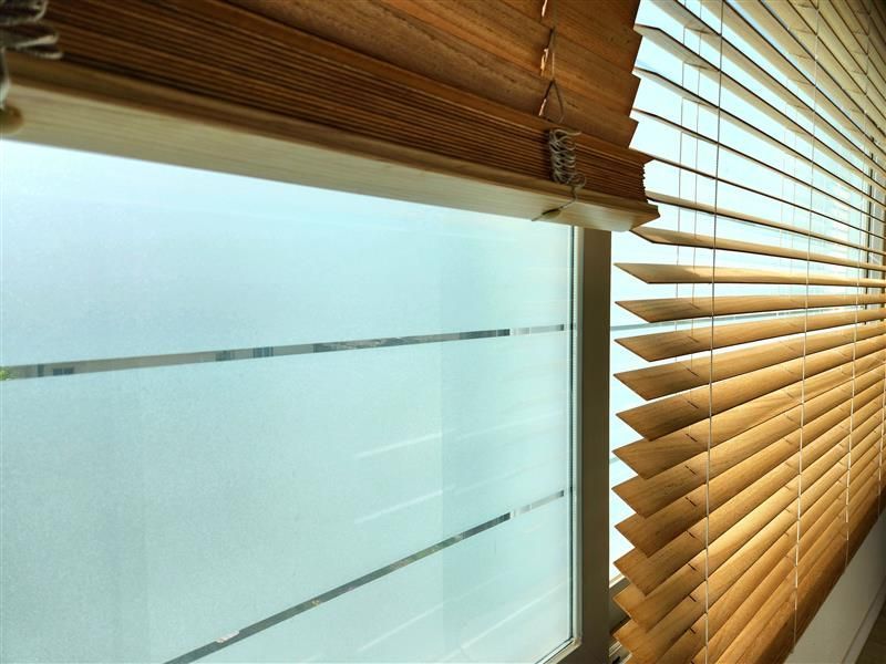 Woman in straw hat smiles, holding wine glass near a lake.