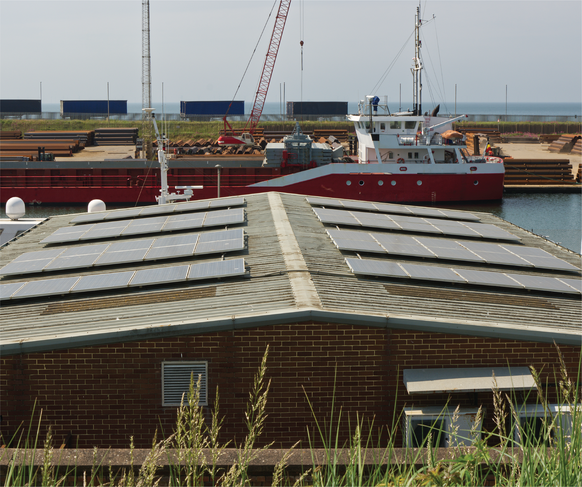 A boat with solar panels on the roof is docked in a harbor