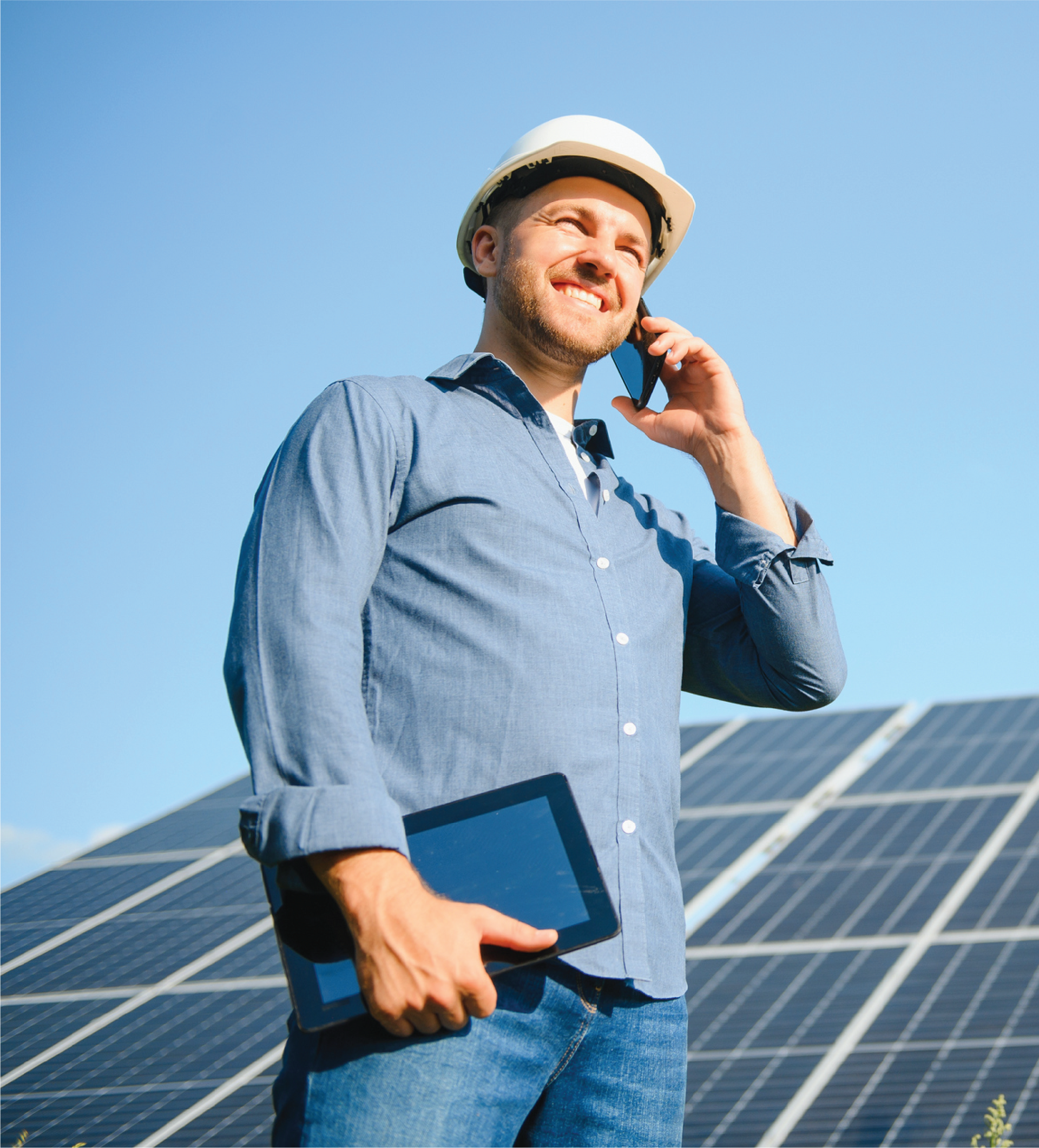 A man is talking on a cell phone while holding a tablet.