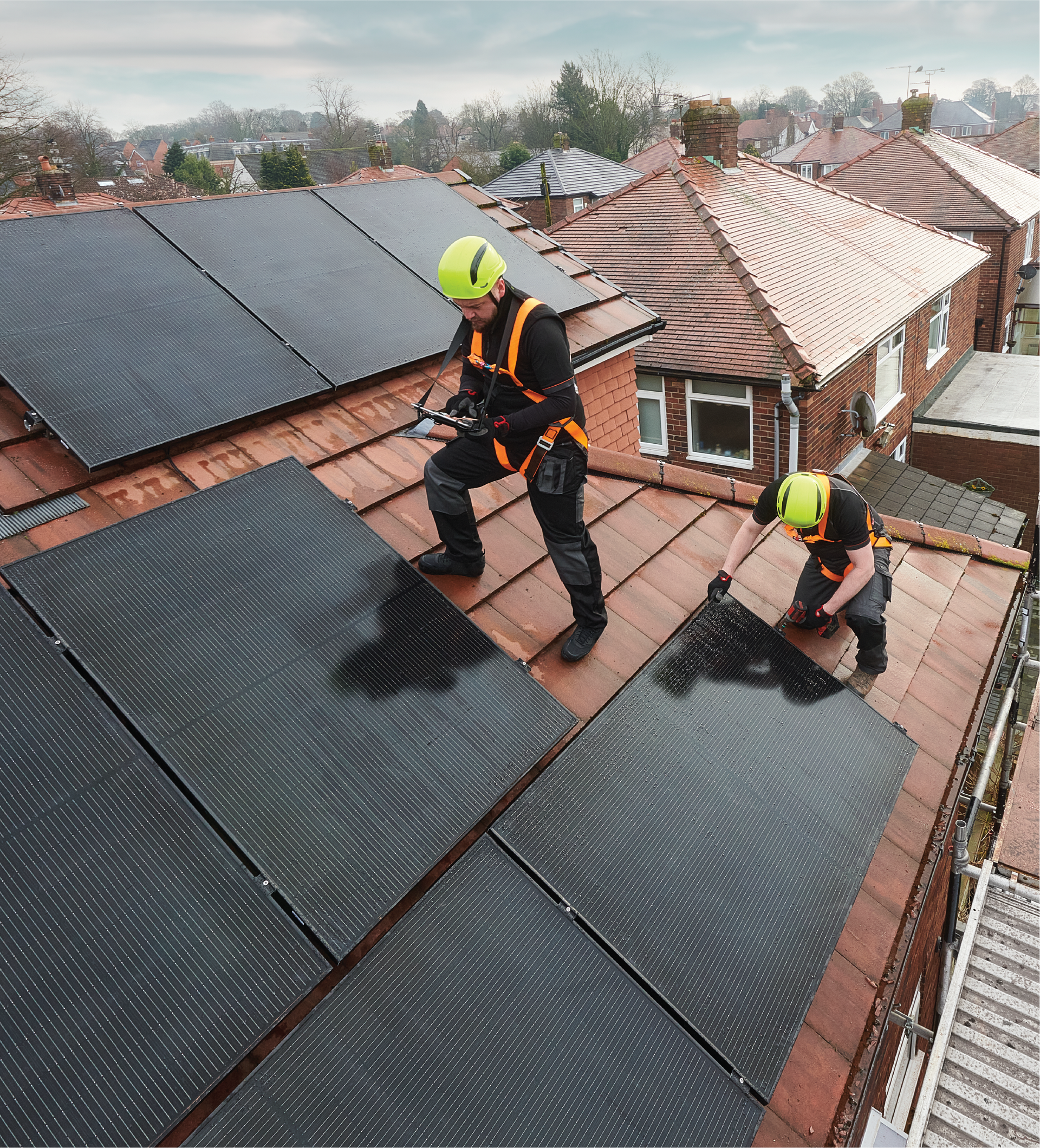 Two men are working on a roof with solar panels.