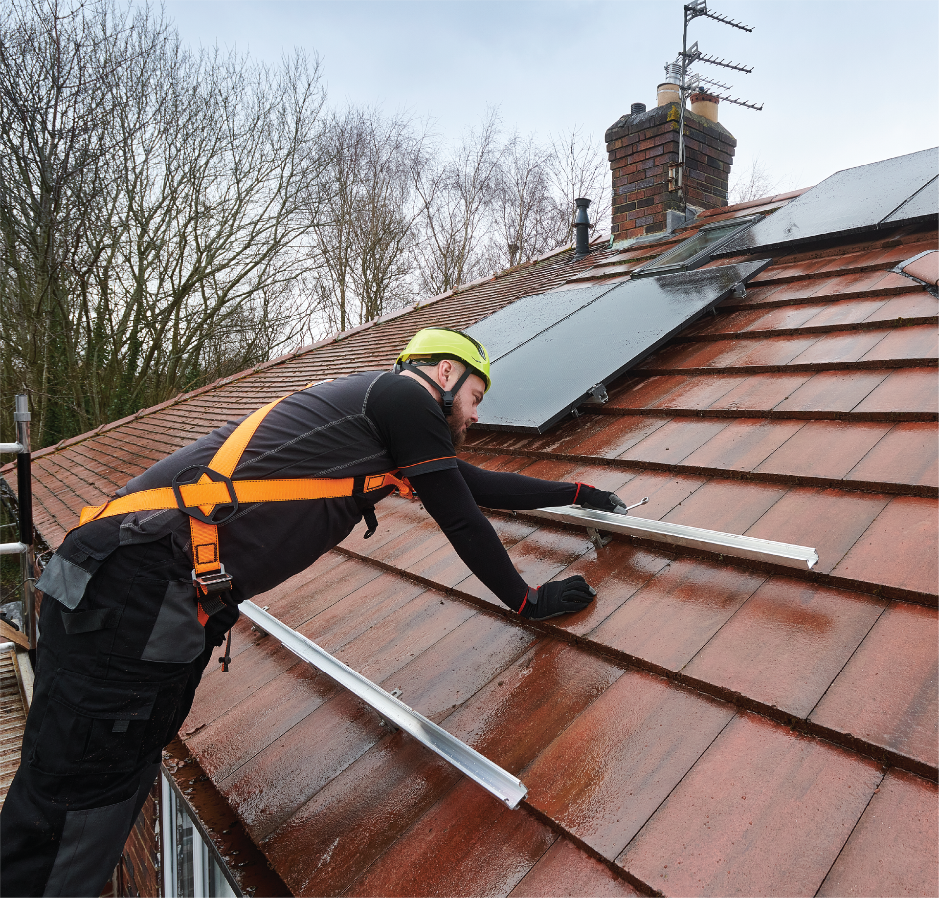 A man is working on a roof with solar panels