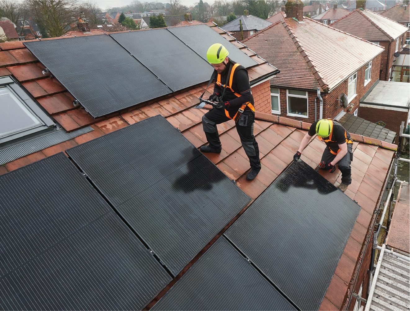 Two men are installing solar panels on the roof of a house