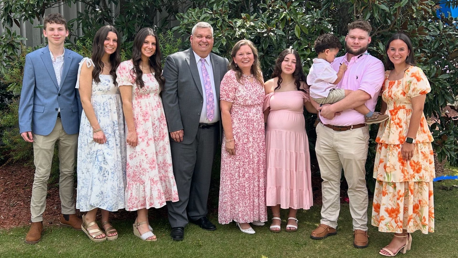 A large family is posing for a picture together in the grass.