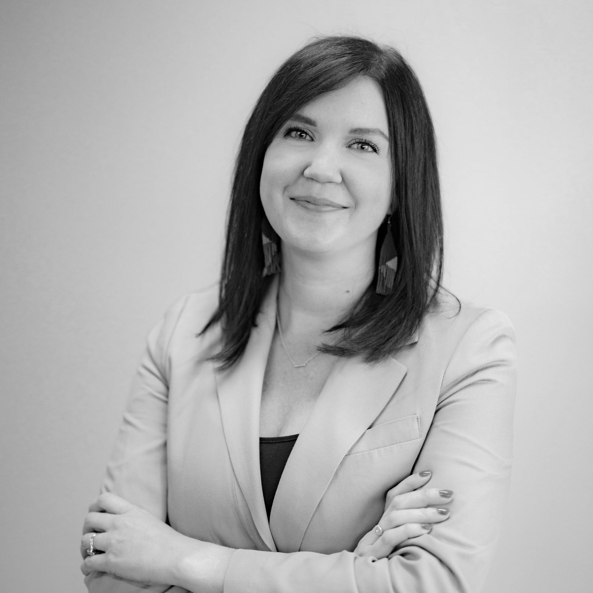 A black and white photo of a woman in a suit with her arms crossed.
