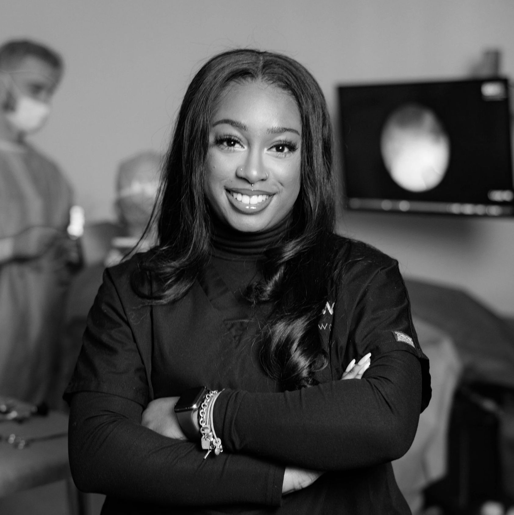 A black and white photo of a woman smiling with her arms crossed.