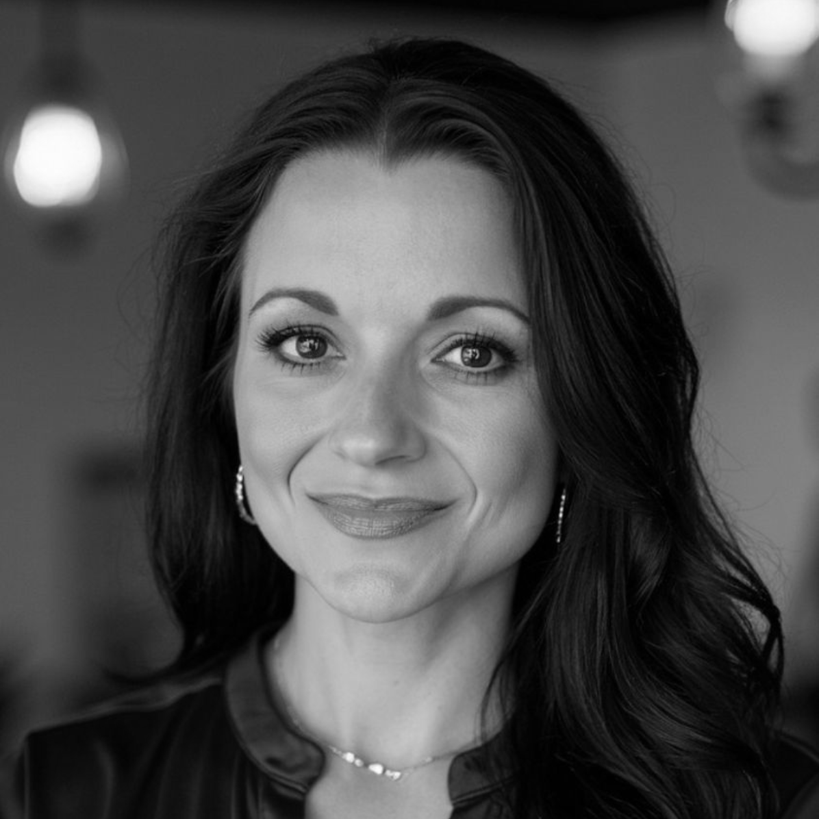 A black and white photo of a woman with a tattoo on her arm.