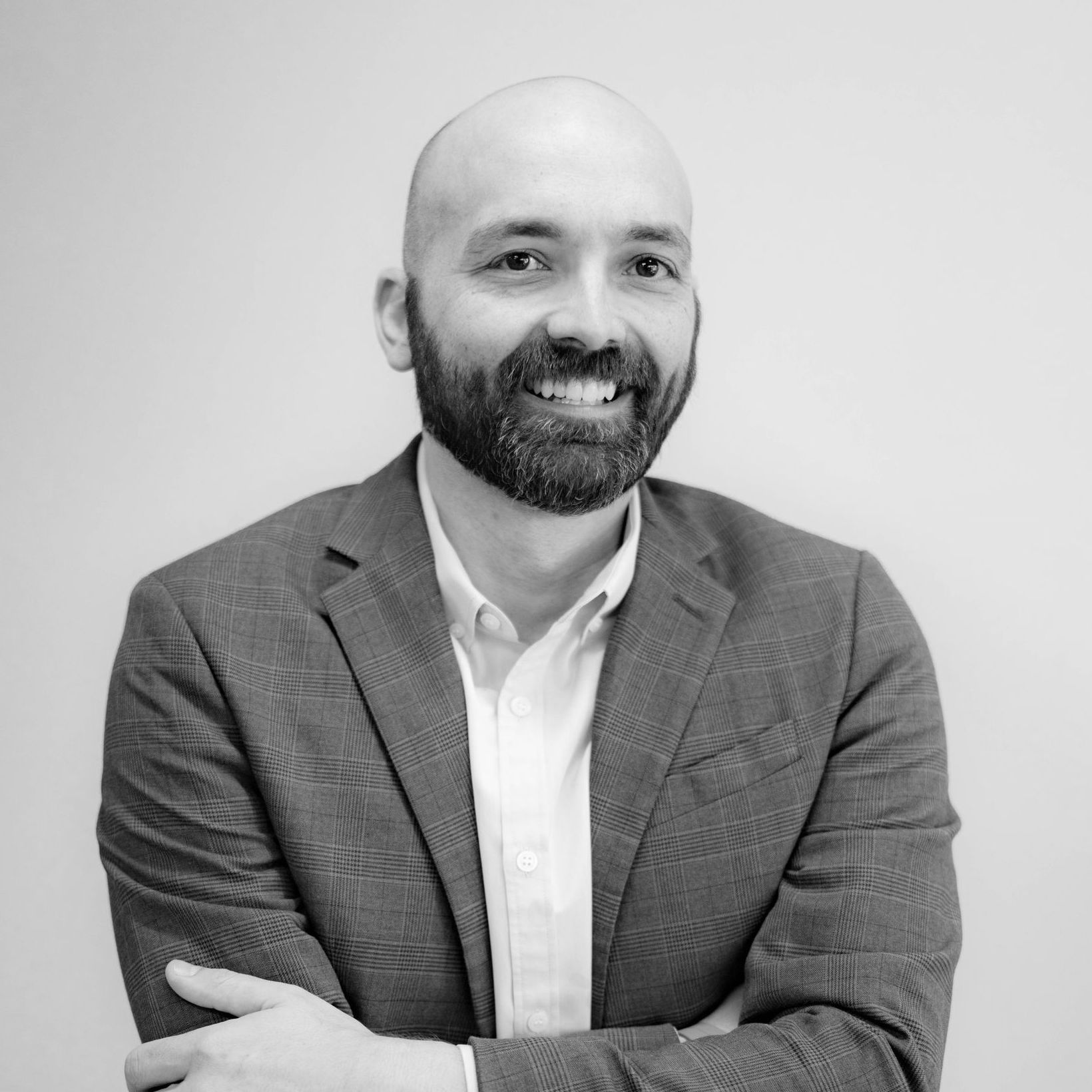 A man with a beard is wearing a suit and smiling in a black and white photo.