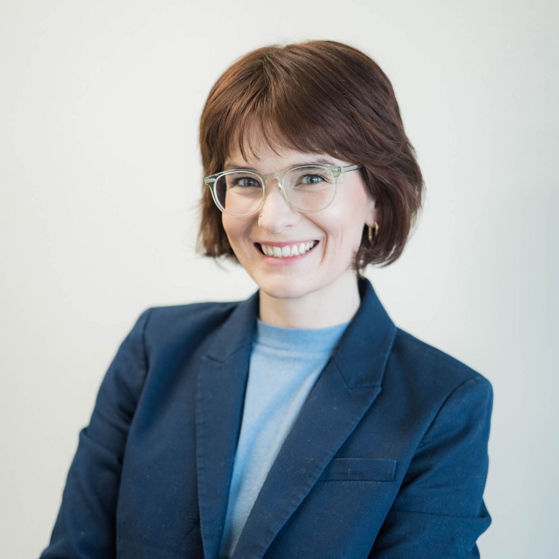 A woman with a tattoo on her arm is wearing a blue shirt and earrings